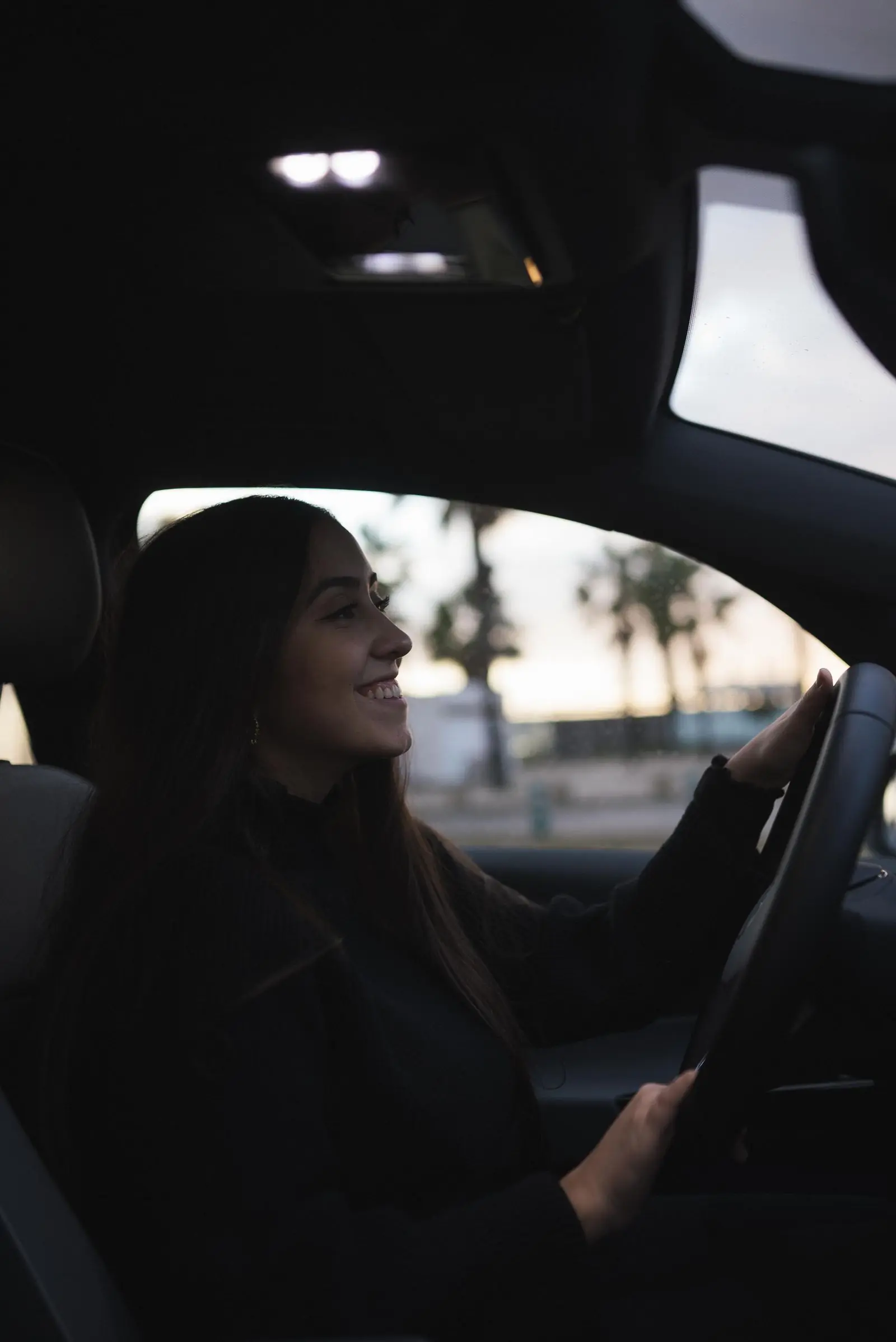 A learner smiling while driving in warm evening light
