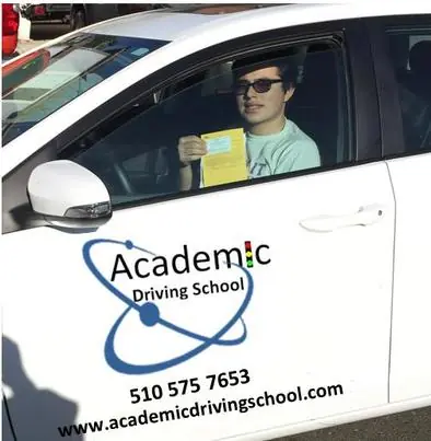 A student in the driver’s seat of a signwritten Academic Driving School car