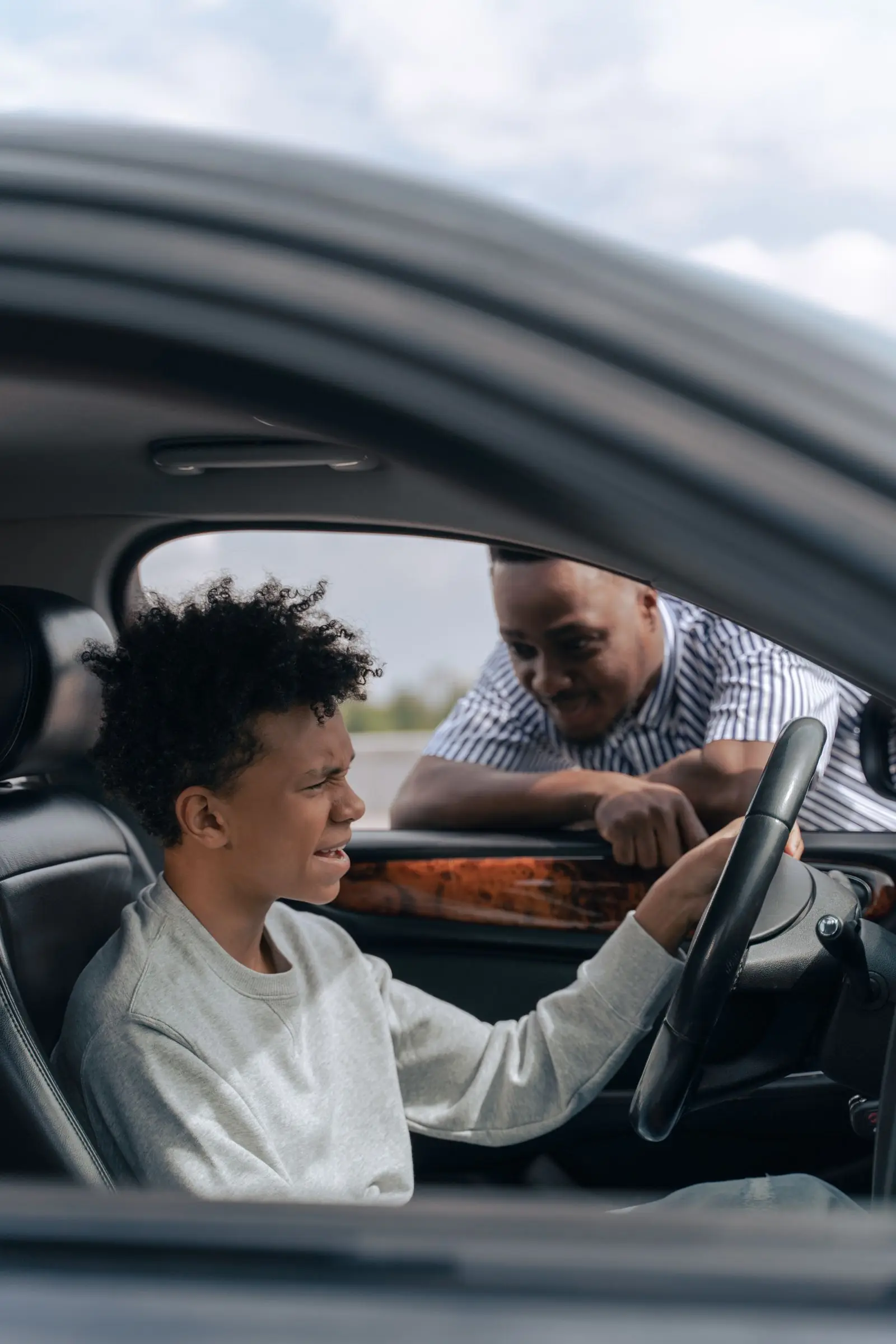 A parent calmly coaching a teenage learner in the driver’s seat