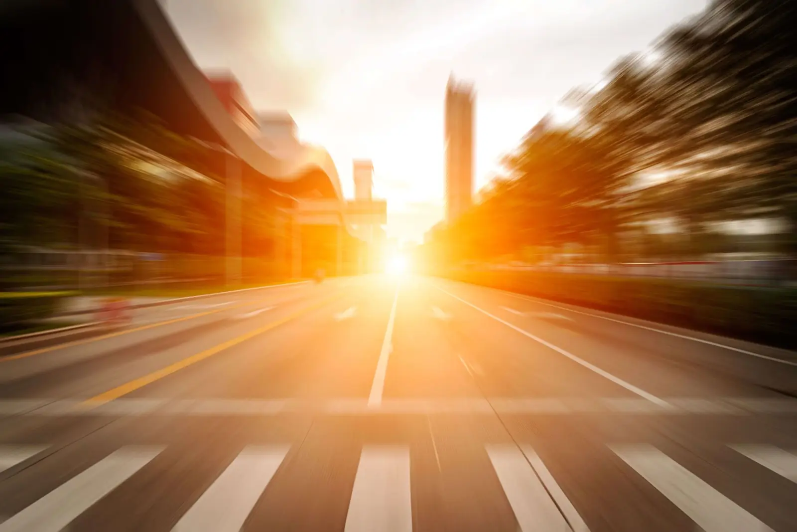 A city road stretching towards a low sun