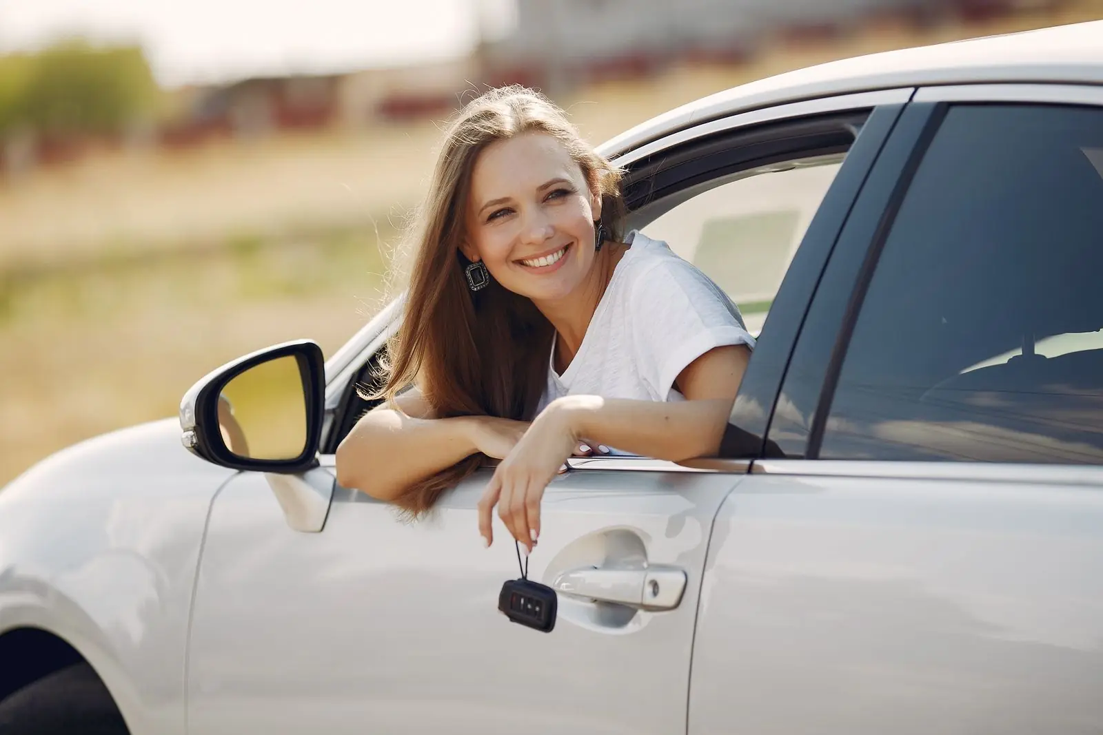 A newly confident driver holding her car keys beside a vehicle