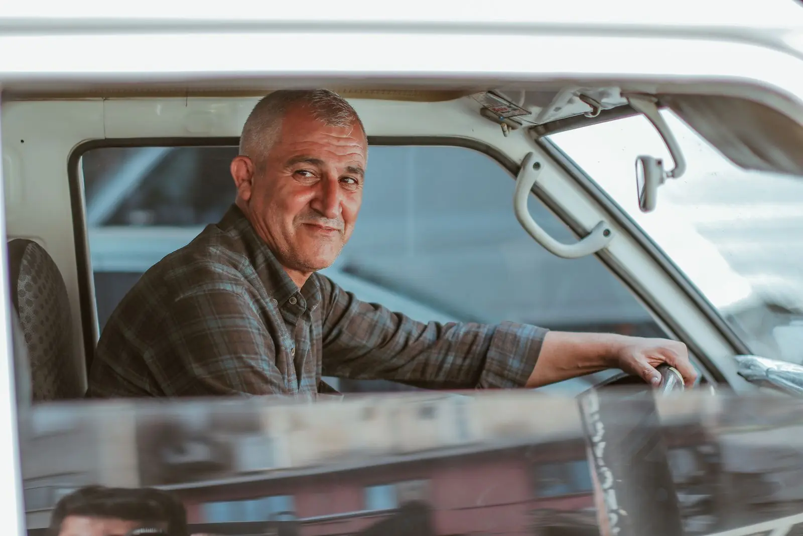 An adult learner smiling behind the wheel