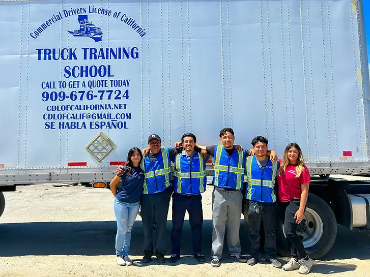 The CDL of California team standing beside the school’s branded training trailer
