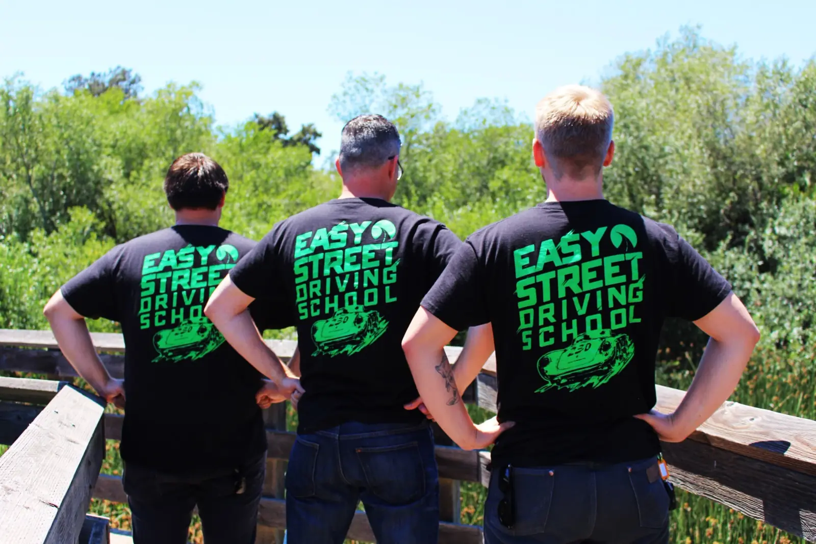 Three Easy Street instructors in branded shirts, looking out over the hills