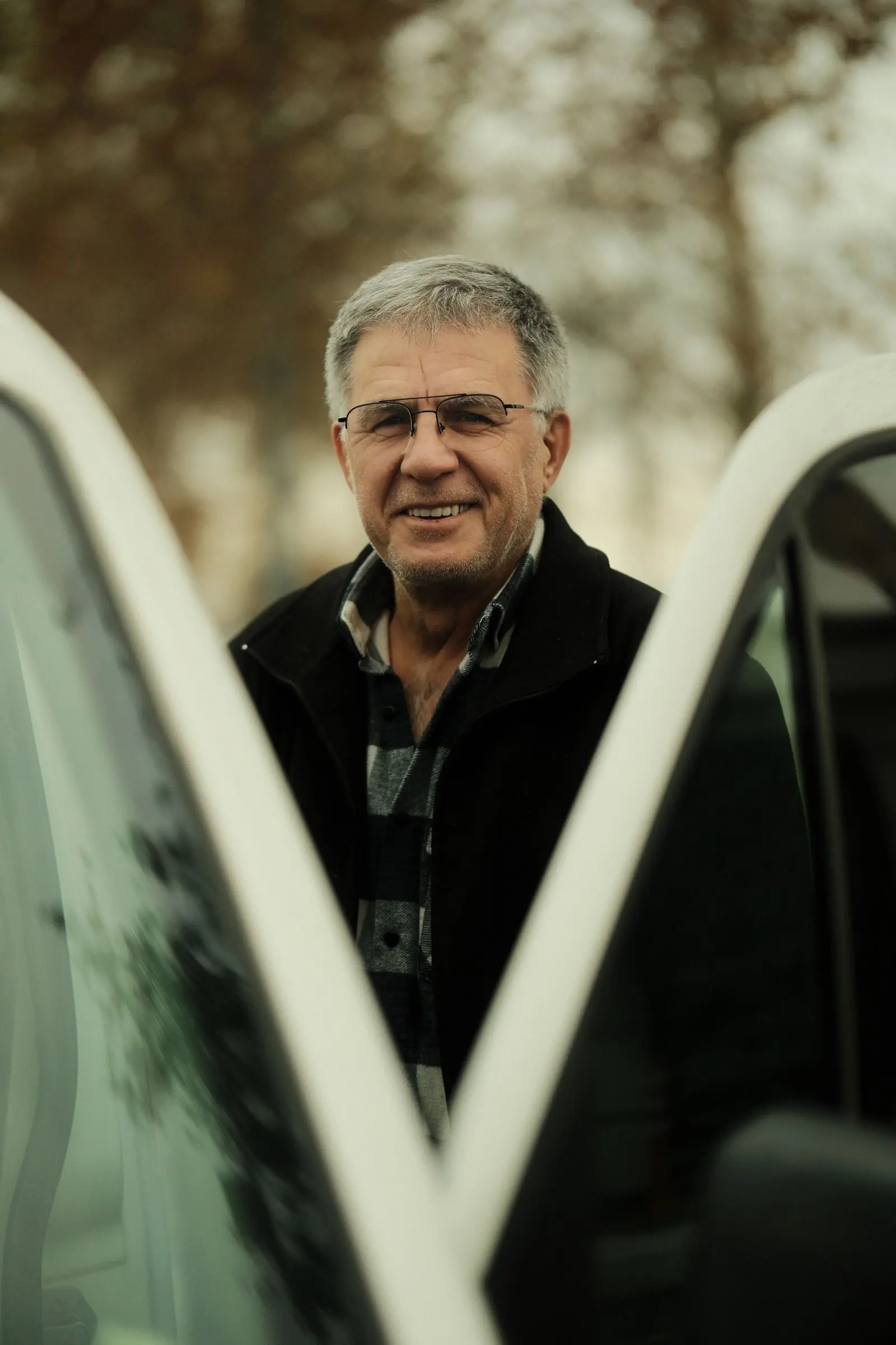 A mature learner smiling beside a car before a lesson