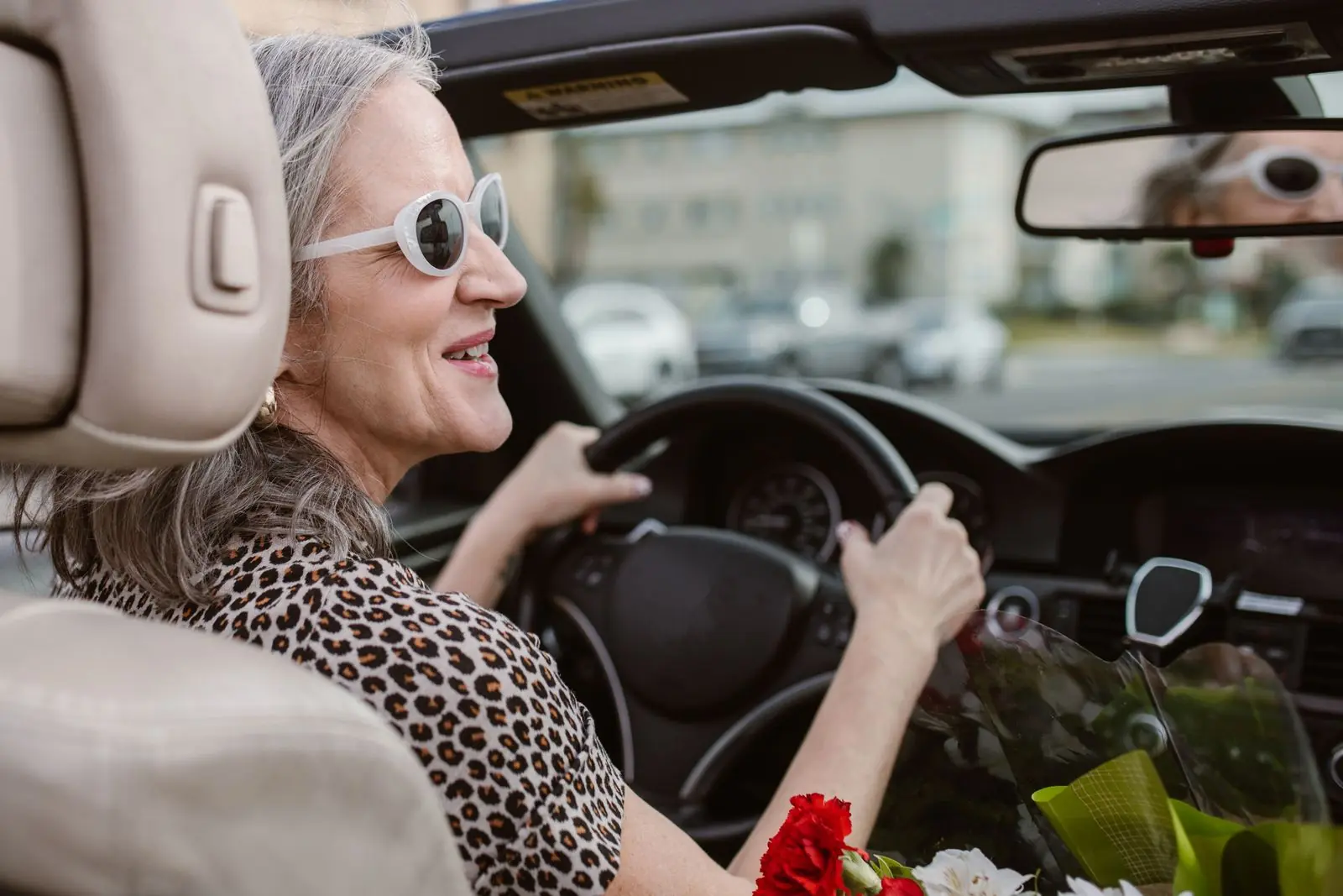 A mature learner smiling while driving on a clear day
