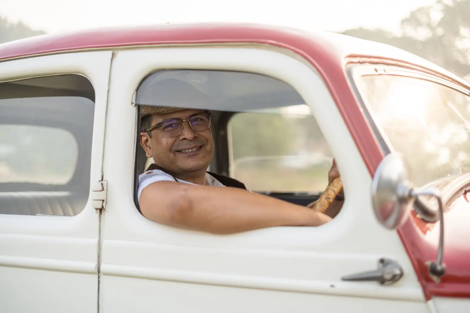 An adult learner smiling behind the wheel on a bright day