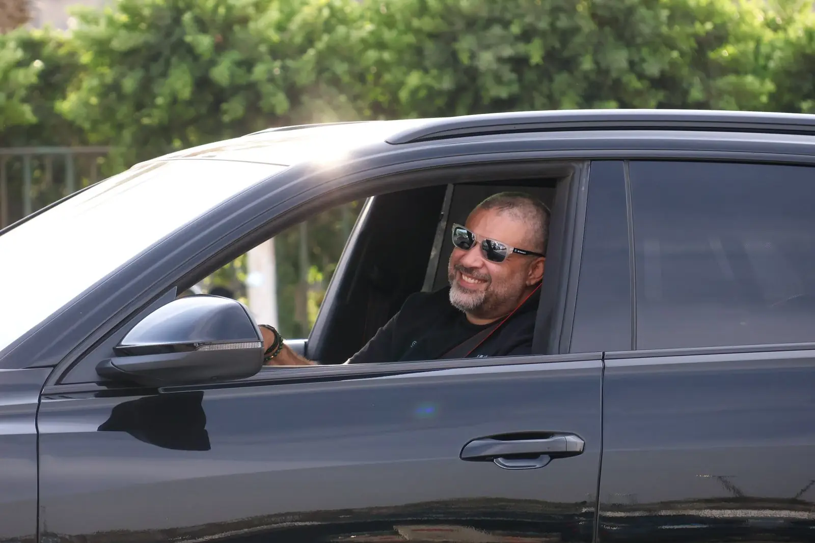 A learner smiling from the driver’s seat of a city car