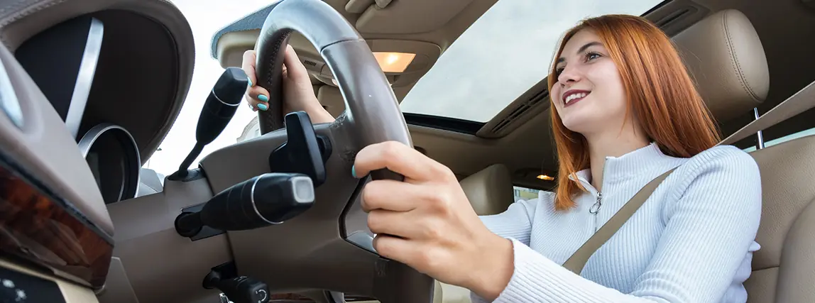 A teenage driver at the wheel with both hands on it, looking ahead