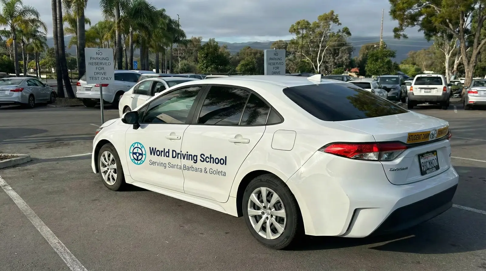 The World Driving School Corolla, marked for Santa Barbara and Goleta, parked in a DMV drive-test bay