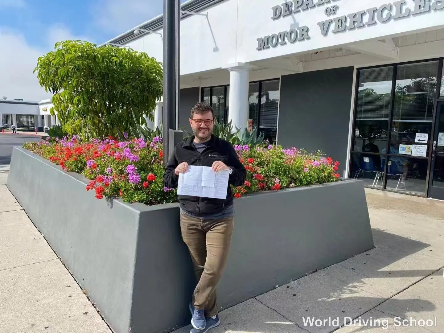 A World Driving School student outside the Santa Barbara DMV holding their drive-test result